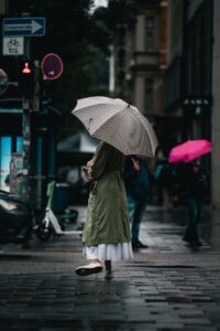 a woman walking down a sidewalk with an umbrella